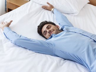happy young man in hotel room bed