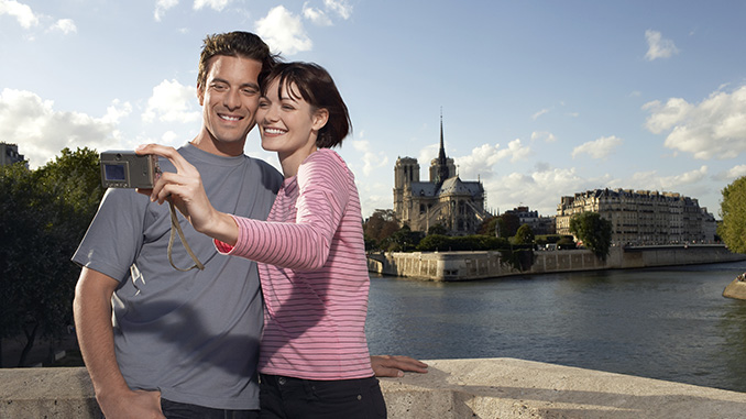 Paris france couple taking a photo of themselves in front of notre dame cathedral